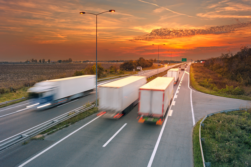 Several trucks in motion blur on the highway at sunset