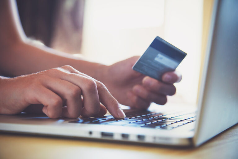 Hands holding credit card and using laptop.