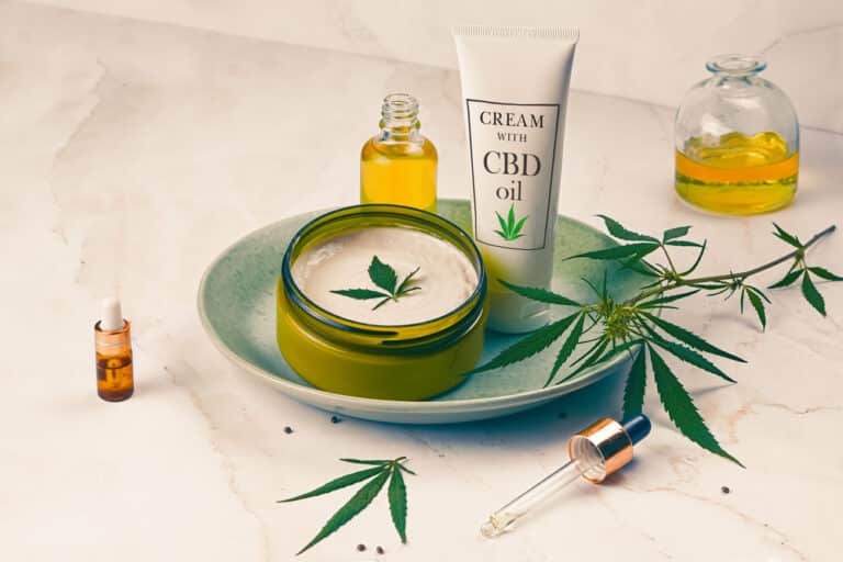 Cosmetics CBD oil on a turquoise plate on a light marble background. Copy space, mockup.