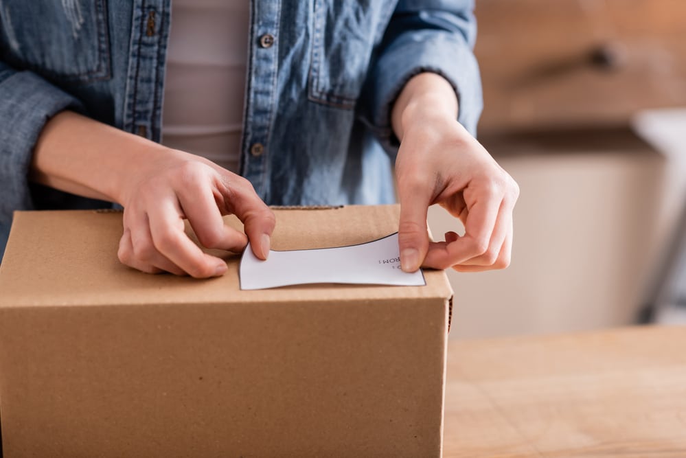 Person applying a pre-printed return label to a package.